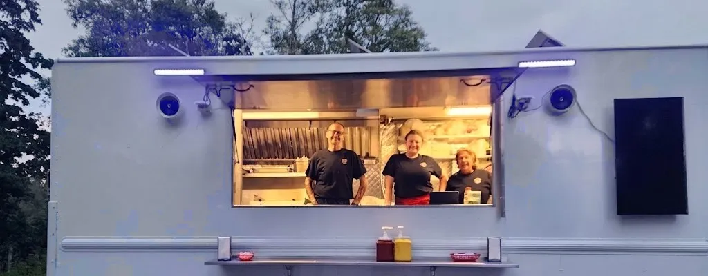 The South Island Lunchbox food truck at dusk with the crew smiling in the serving window